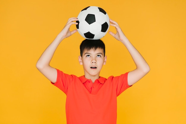 Мальчик держит футбольный мяч на голове