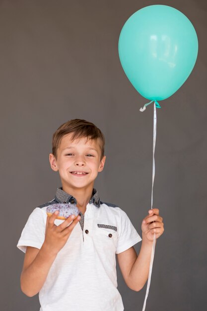 Boy holding a glazed doughnut and a balloon