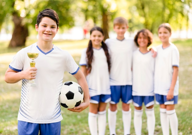 Boy holding a golden trophy next to his team mates