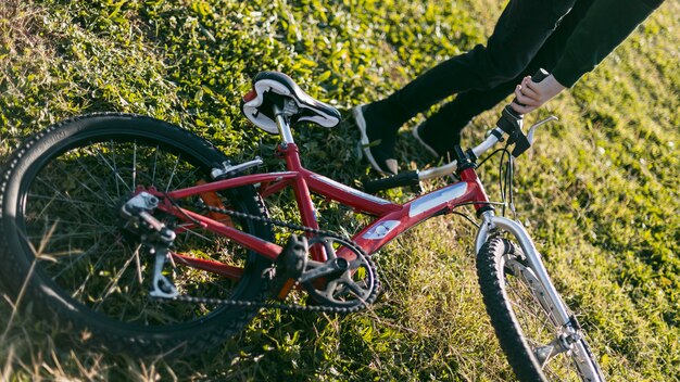 Boy holding his bike on grass