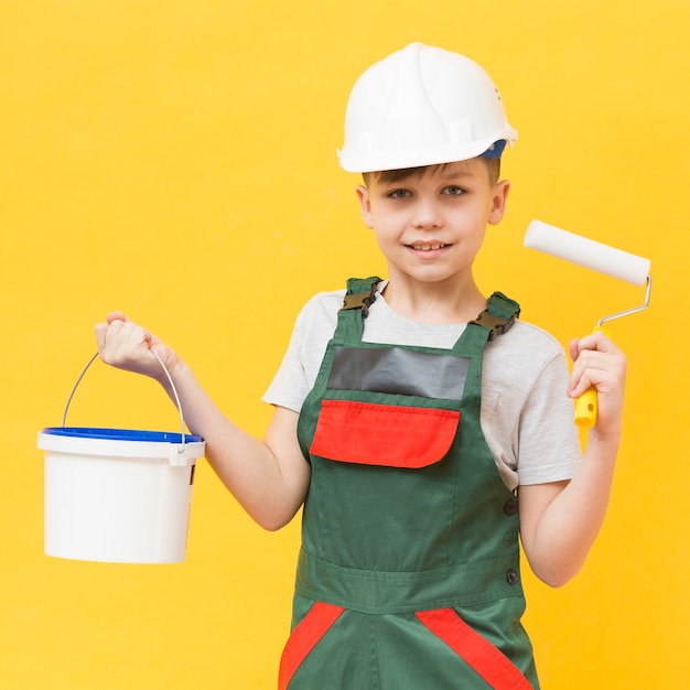 Foto gratuita colpo medio del rullo di pittura della tenuta del ragazzo