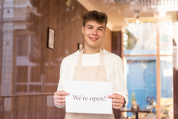 Boy holding a we're open sign after the end of quarantine