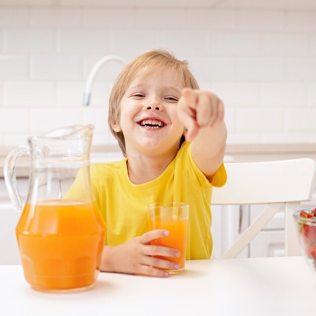 Boy at home in kitchen pointing