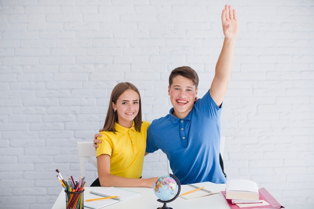 Boy hugging girl and holding hand up