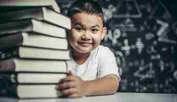 Free photo a boy hugging a pile of books.