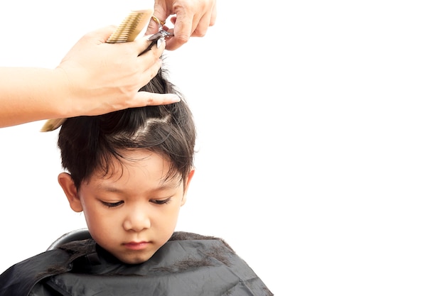 A boy is cut his hair by hair dresser isolated over white background