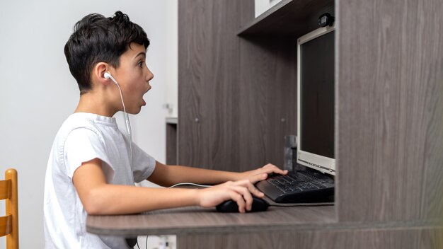 Boy is using PC with headphones. Amazed and exited face