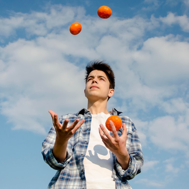 Бесплатное фото Мальчик жонглирует апельсинами на свежем воздухе
