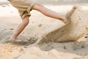 Free photo boy kicking sand at beach