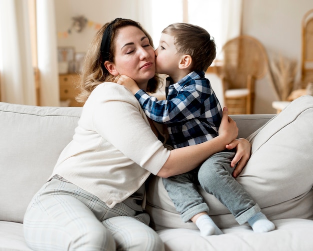 Boy kissing her mother front view