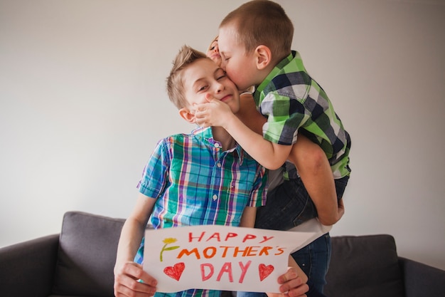 어머니의 날에 그의 동생을 키스하는 소년