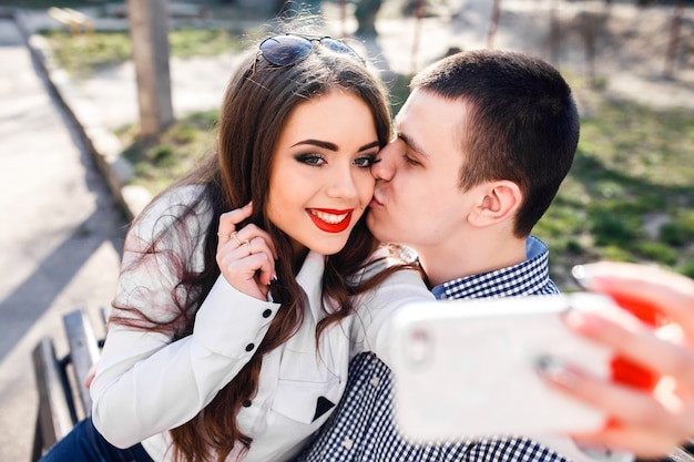 Boy kissing his girlfriend while taking a photo