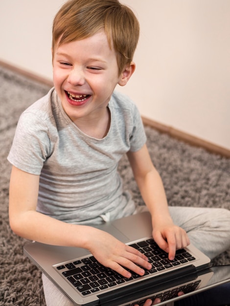 Boy laughing while holding a laptop
