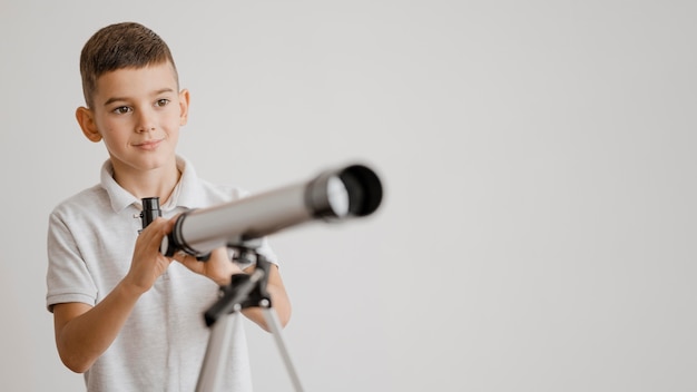 Boy learning how to use a telescope with copy space