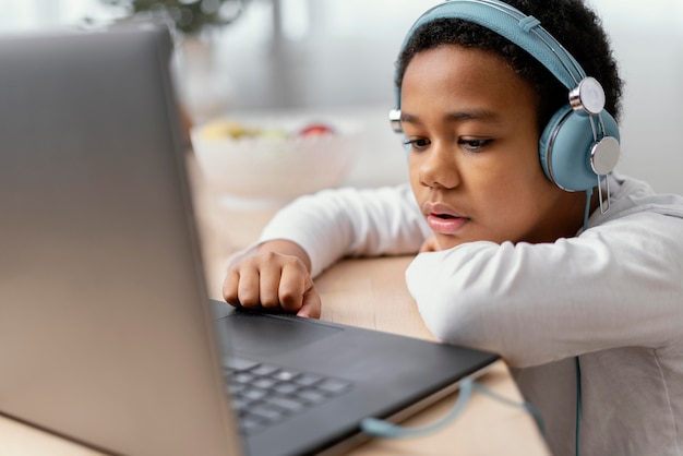 Бесплатное фото Мальчик слушает музыку и использует ноутбук