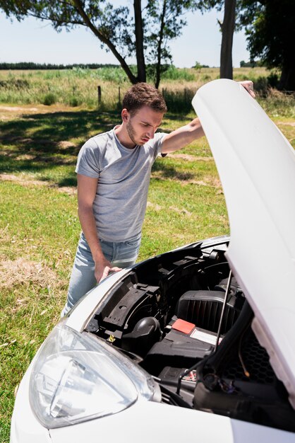 Boy looking at broken down car