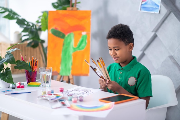 Boy looking at brushes sitting at table