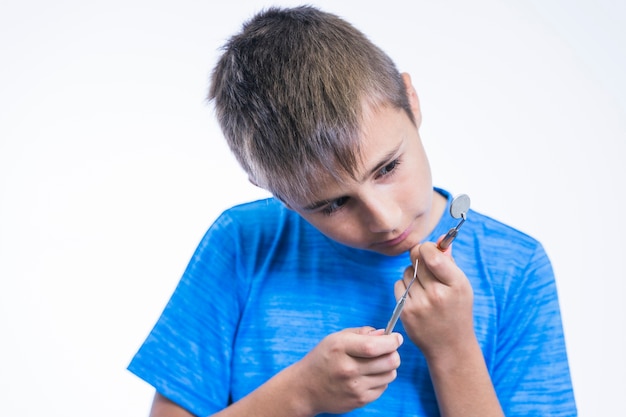 Boy looking at dental mirror and scaler