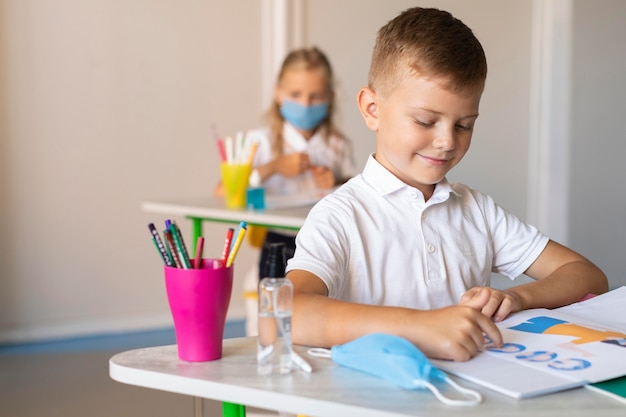 Foto gratuita ragazzo che guarda il suo libro in classe