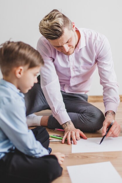 Boy looking at his father while drawing