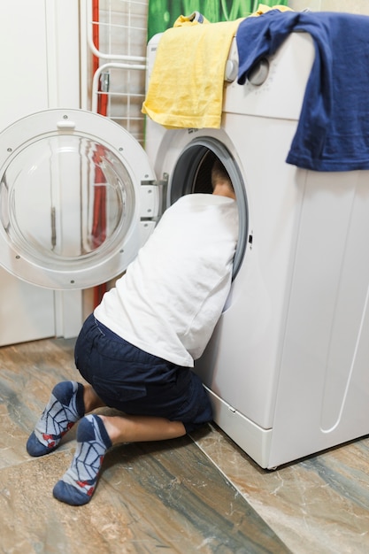 Free photo boy looking inside washing machine