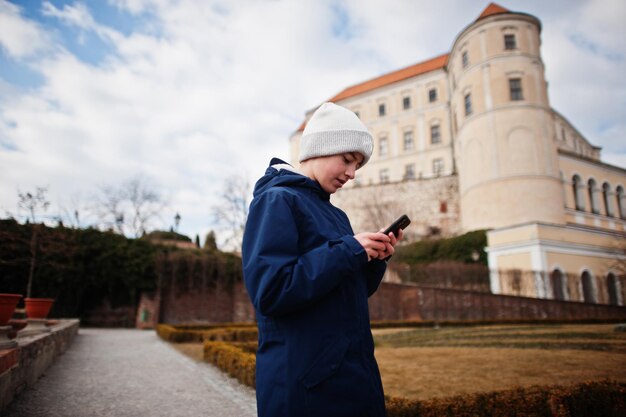 歴史的なミクロフ城モラビアチェコ共和国の古いヨーロッパの町で電話を見ている少年