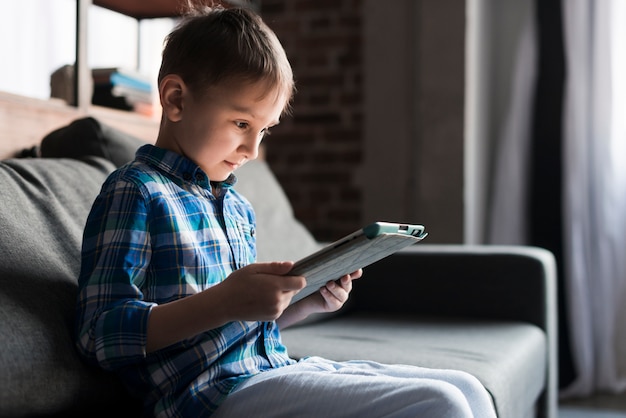 Boy looking at tablet on couch