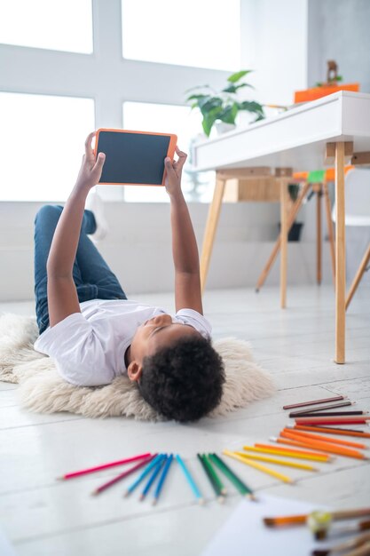 Boy lying on floor taking selfie on tablet