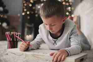 Free photo boy lying on front and drawing