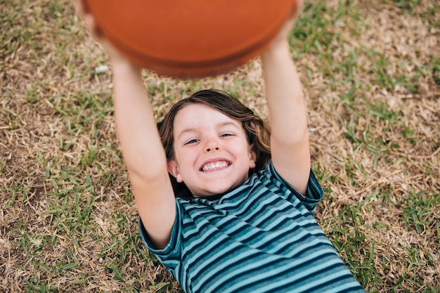 Boy lying on grass and holding ball