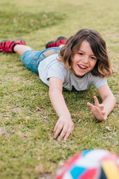 Foto gratuita ragazzo che si trova nell'erba e che gioca con la palla