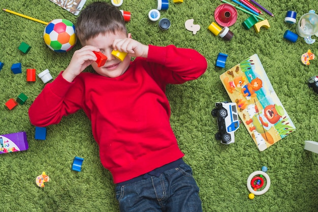 Free photo boy lying in mess of toys