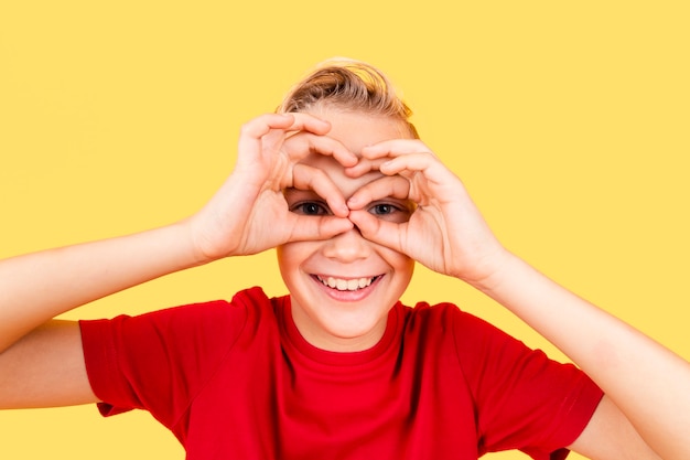 Free photo boy making binocular with hands on his eyes