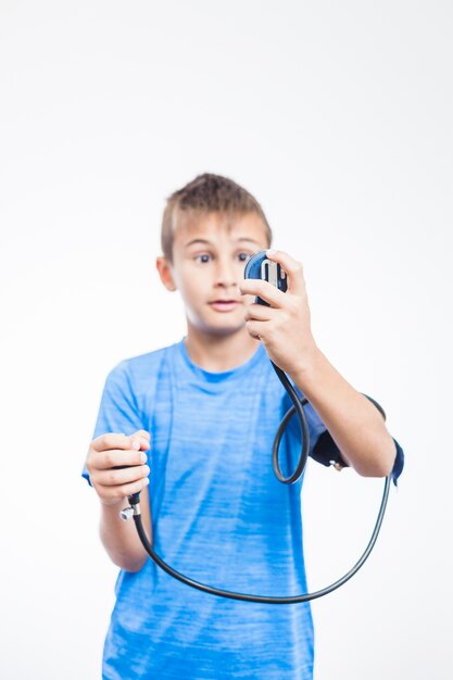 Boy measuring blood pressure on white backdrop