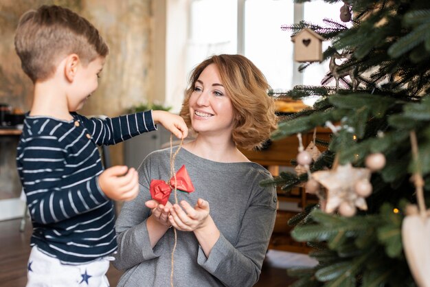 木の装飾を保持している男の子と母親