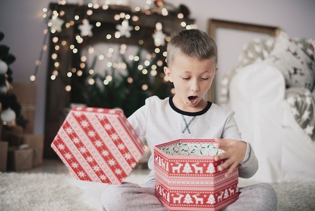 家でクリスマスプレゼントを開く男の子