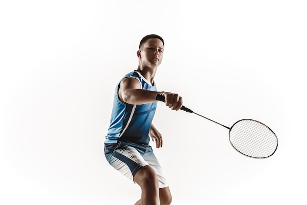 Boy playing badminton isolated on white wall.