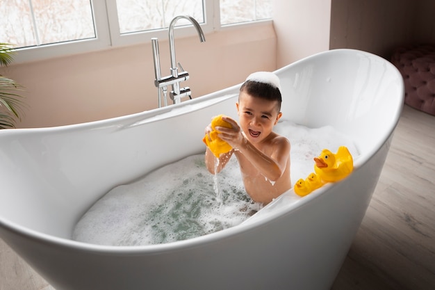 Free photo boy playing in bathtub high angle