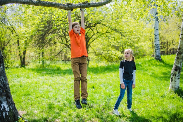 Boy playing on a branch while his sister looks at him