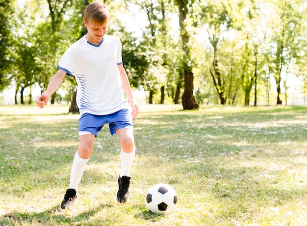 Foto gratuita ragazzo che gioca a calcio da solo