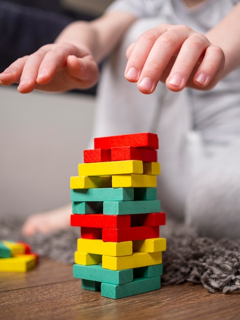 Free photo boy playing with colorful wooden tower game