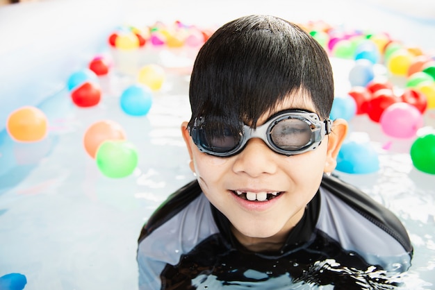 Boy playing with colourful ball in small swimming pool toy