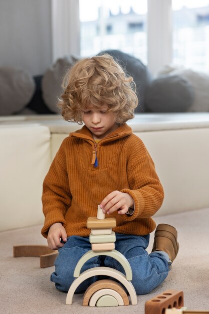 Boy playing with eco toys indoors full shot