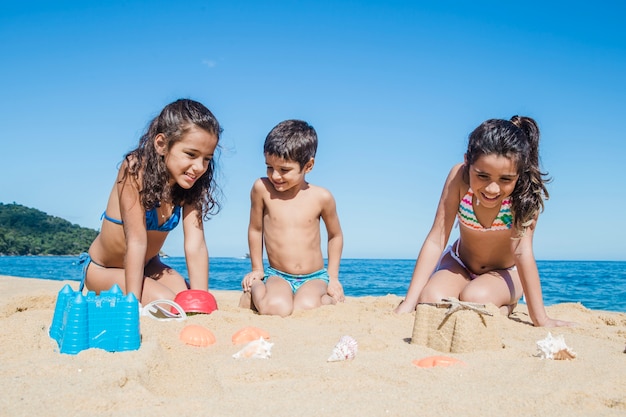 Бесплатное фото Мальчик играет со своими сестрами на песке