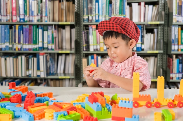 図書室の学校でプラスチック製のブロックで遊んでいる少年