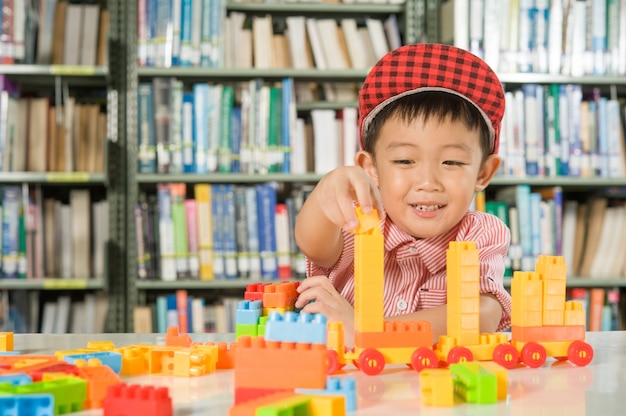 図書室の学校でプラスチック製のブロックで遊んでいる少年