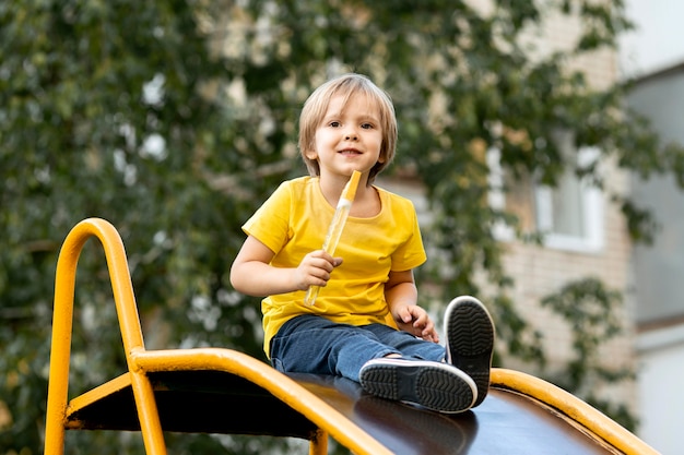 Free photo boy playing with soap bubbles in park