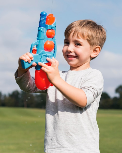 Мальчик играет с водным пистолетом, вид спереди