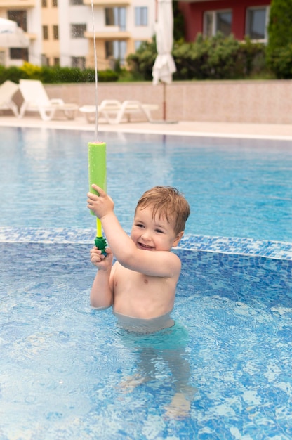 Foto gratuita ragazzo in piscina giocando con la pistola ad acqua