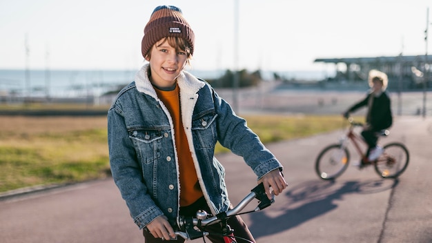 Free photo boy posing while his friend is riding his bike